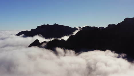 Aerial-view-overlooking-mountain-peaks-and-clouds,-in-Madeira---tracking,-drone-shot