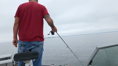 man fishing off of boat on lake in summer