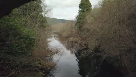 Imágenes-Aéreas-Que-Vuelan-Debajo-De-Un-Puente-En-Desuso-En-Los-Vestíbulos-Del-Río-Mirando-Hacia-El-Lago-Ness,-Tierras-Altas-Escocesas,-Escocia