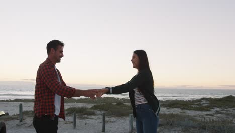 happy caucasian couple dancing on the beach by the sea