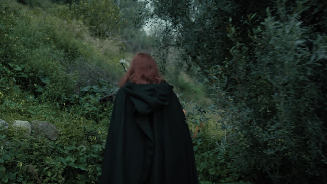 una mujer enigmática camina por el bosque de cuentos de hadas por la noche con una linterna.