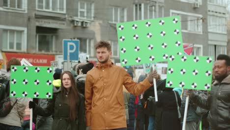 white and dark skinned protest activists at city riot with greenscreen banners.