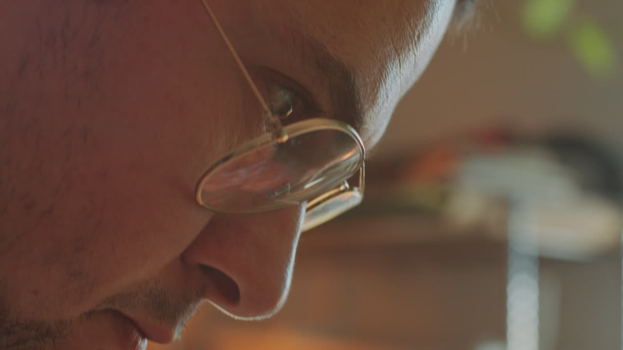 primer plano de un artista concentrado con gafas pintando en el estudio