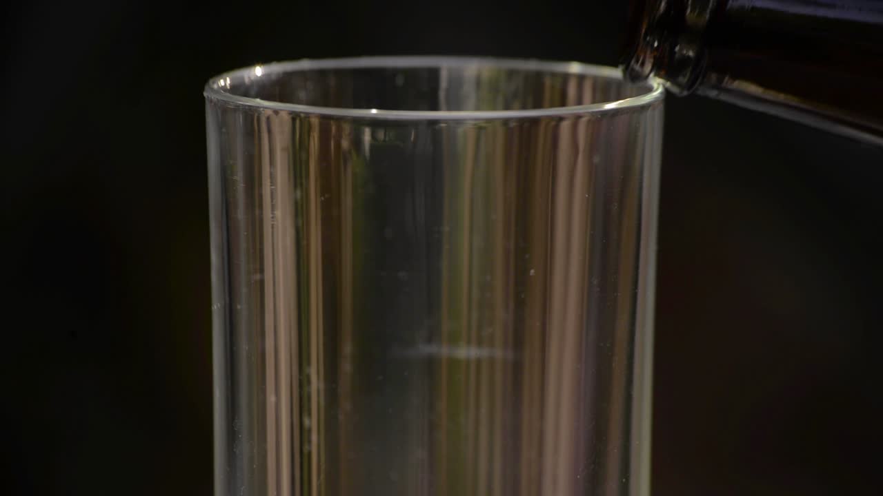 해질녘에 흐릿한 필스너 에일 맥주가 유리잔에 쏟아지고 있다