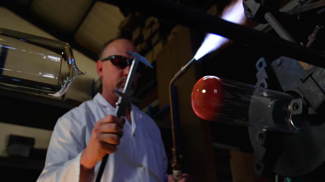 trabajador masculino caucásico maduro creando vidrio en una fábrica de vidrio 4k