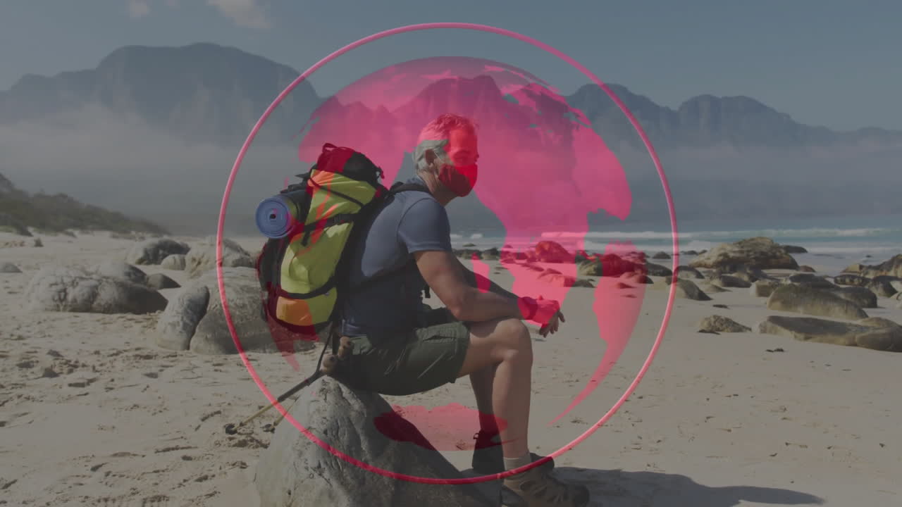 male hiker with pack holding poles, sitting on beach rock displaying data globe overlay for tech