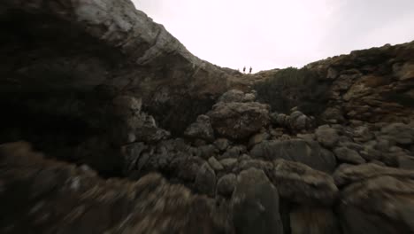 fpv drone shot flying through natural rock arch along the seaside in mallorca, spain during evening time