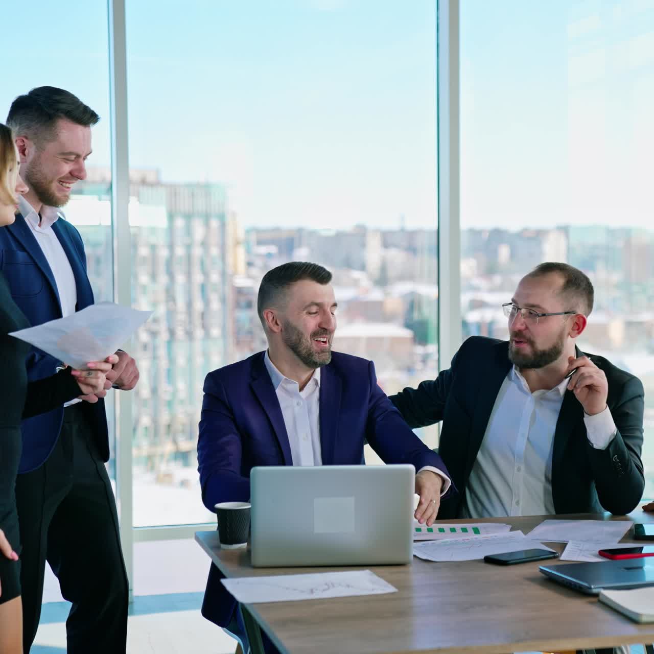 Teamwork of business people on a beautiful city window view. Group of young entrepreneurs having a pleasant conversation in the office center