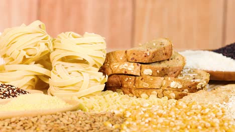a hand organizes various grains and breads on a wooden table with warm lighting, emphasizing texture and variety