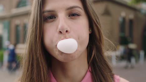 slow motion close up  portrait of young beautiful woman student blowing bubble gum wearing pink shirt