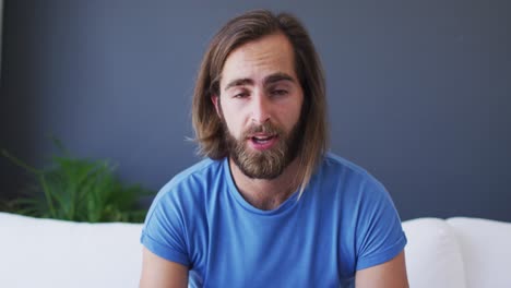 portrait of caucasian man talking on videocall while sitting on the couch at home