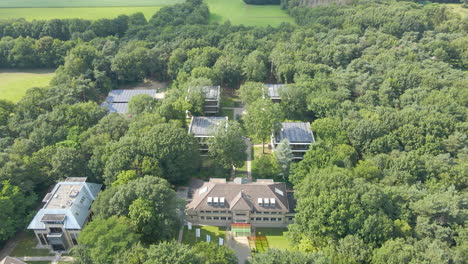 aerial of inspirational office buildings with solar panels on rooftop surrounded by green forest in summer