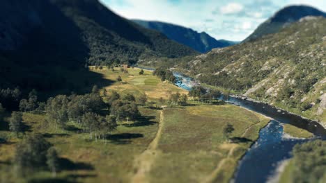 Aerial-view-of-the-river-flowing-through-the-lush,-wide,-rocky-valley