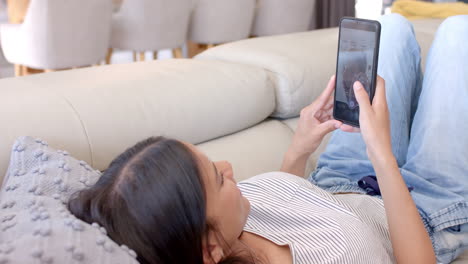 lying on couch, teenage girl using smartphone and relaxing at home