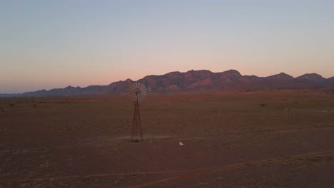 Aerial-flying-through-Old-Rusty-windmill,-Wilpena-Pound-desert-location,-Australia