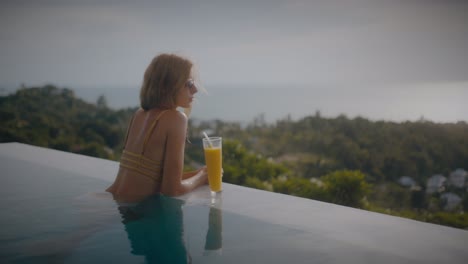 woman relaxing by pool with a drink