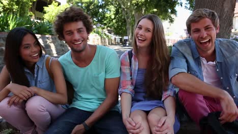 gelukkige studenten zitten buiten en glimlachen naar de camera