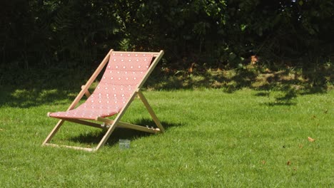 sunlounger on green grass in vibrant garden, handheld view