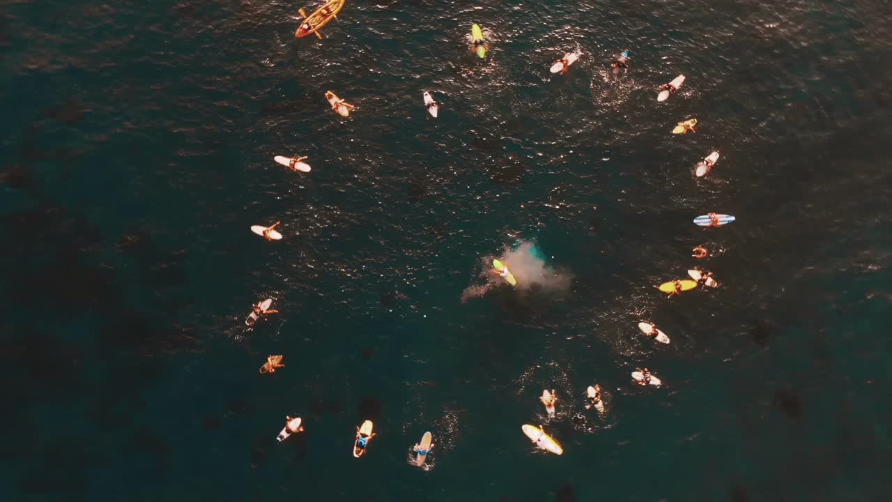 공중: 서퍼 들 의 집단 이 바다 에서 원 을 형성 하고 일부 는 의식 으로 물 을  ⁇ 고 있다