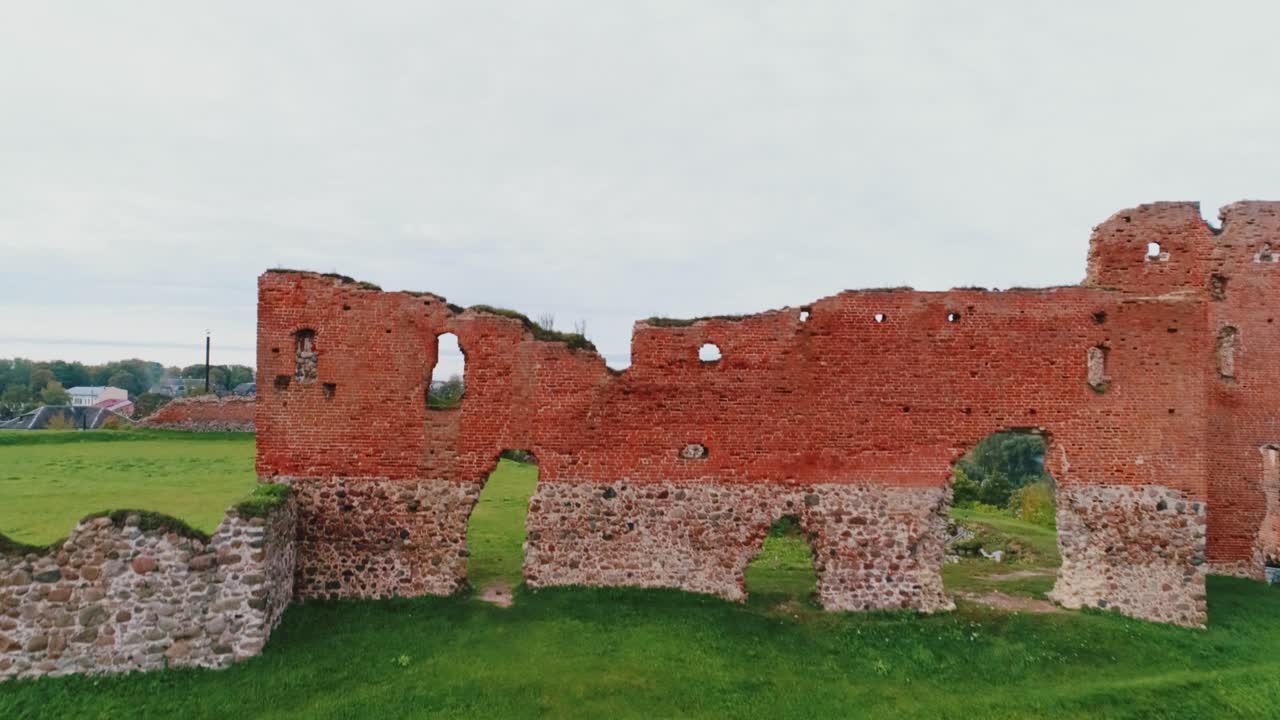 Medieval ruins of Ludza Castle rise above green hill, Establishing Shot, Latvia