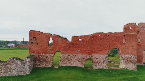 medieval ruins of ludza castle rise above green hill, establishing shot, latvia