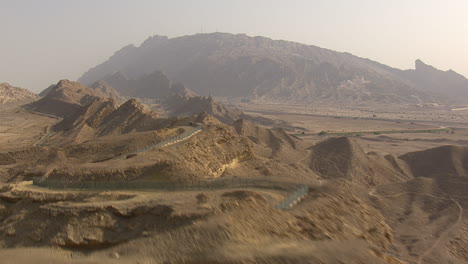 Aerial-revealing-shot-of-the-stunning-curvy-roads-at-Jabel-Hafeet-in-Al-Ain,-UAE