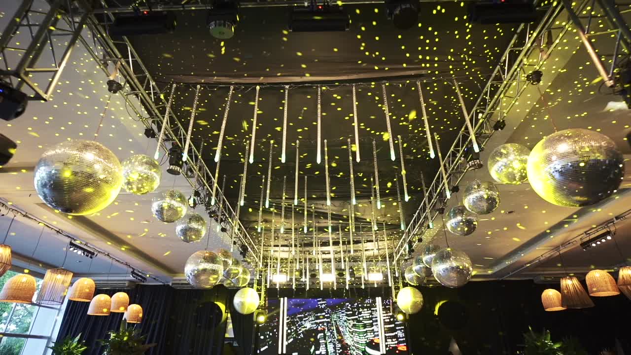 A beautifully decorated wedding venue with hanging lights and disco balls creating a festive atmosphere