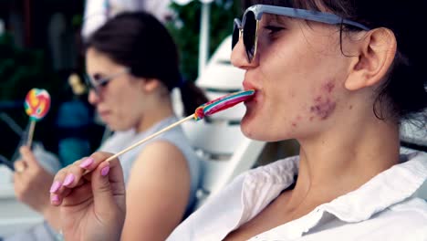 friends licking lollipop by the pool and dancing on the music