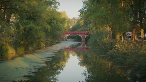 Lis-River-In-Leiria-Portugal-During-The-Summer-With-A-Red-Bridge-And-People-Crossing-In-The-Distance