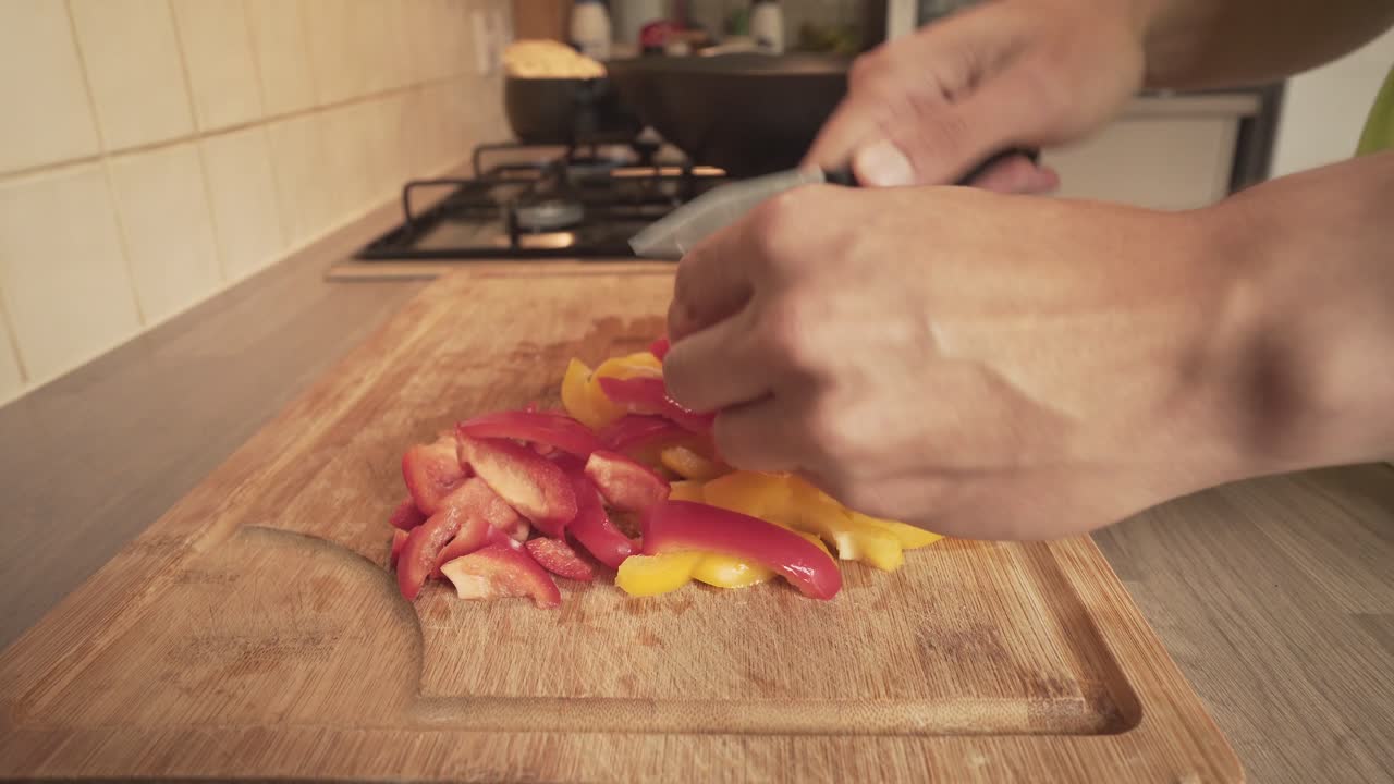 persona cortando pimientos rojos y amarillos en una tabla de madera en casa