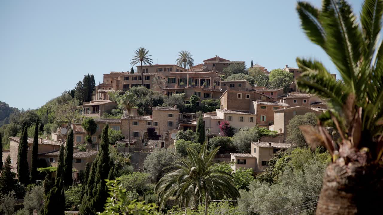 Traditional Mediterranean village in Mallorca surrounded by green hills and palm trees