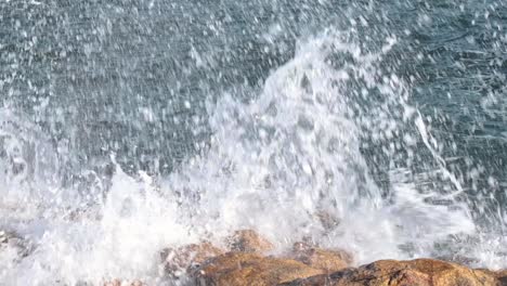 slow motion of awesome power of waves breaking over rocks on a sunny day