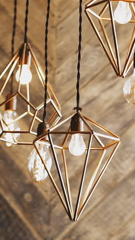 slow motion: numerous different stylish steam-punk metal lusters and light bulbs hang on ceiling in spacious room against decorative wooden wall