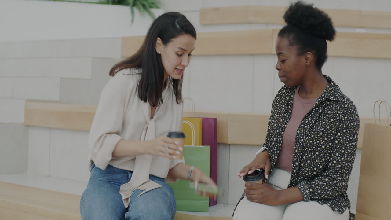 Two Women Discussing on a Smartphone in a Cafe
