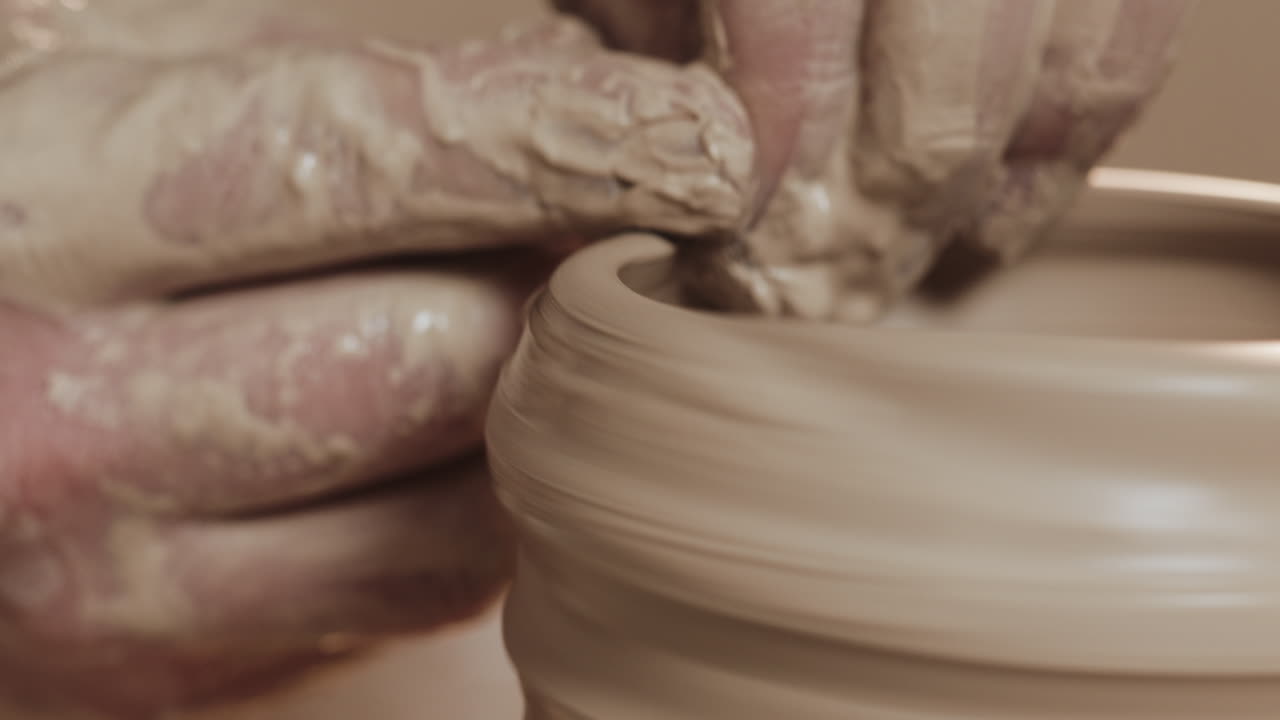 primer plano de un alfarero moldeando arcilla en una rueda de cerámica