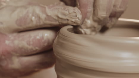close-up van een pottenbakker die klei vorm geeft op een pottenbakwiel