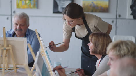 side view of a happy senior people smiling while drawing as a recreational activity or therapy in paint class together with the group of retired women and men