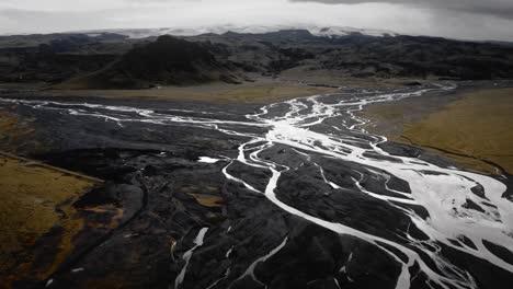 Wunderschöne-Gletscherflüsse-Aus-Der-Luft,-Die-Durch-Schwarze-Vulkanlandschaft-Fließen,-Island-Landschaft