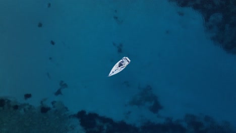 drone de arriba hacia abajo estática de velero anclado en impresionante agua azul transparente del océano