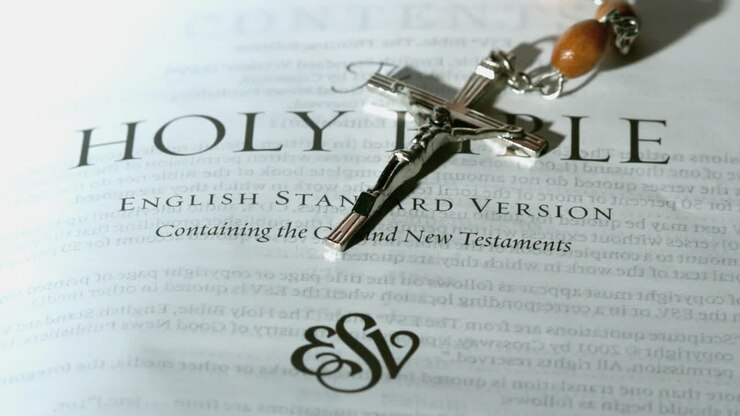 Rosary beads falling onto first page of the holy bible