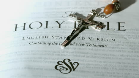 rosary beads falling onto first page of the holy bible