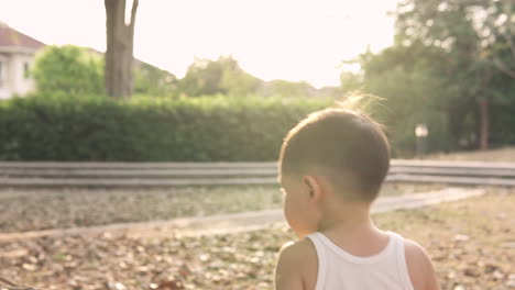 一位可愛英俊的亞洲男孩在日落時在公園外散步和玩玩具的慢動作片段,