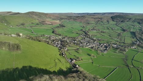 Wide-aerial-push-in-shot-towards-the-Peak-District-town-of-Castleton,-UK