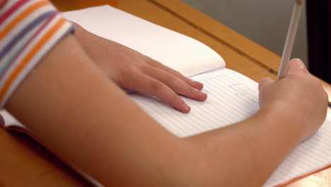 schoolchild writing in notepad at school