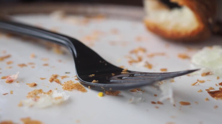 Close-up of a plastic fork on a plate with crumbs