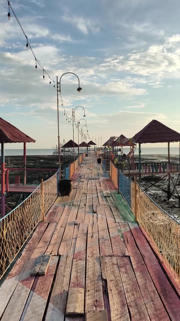 Dermaga Kayu Berwarna-warni dengan Gazebo Memanjang ke Lautan Saat Air Surut
