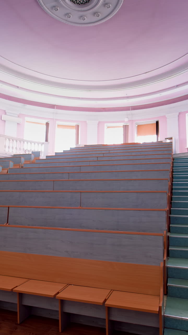 Beautiful conference hall with empty seats. Modern auditorium with wooden desks for lectures. Spacious university classroom without people. Vertical video