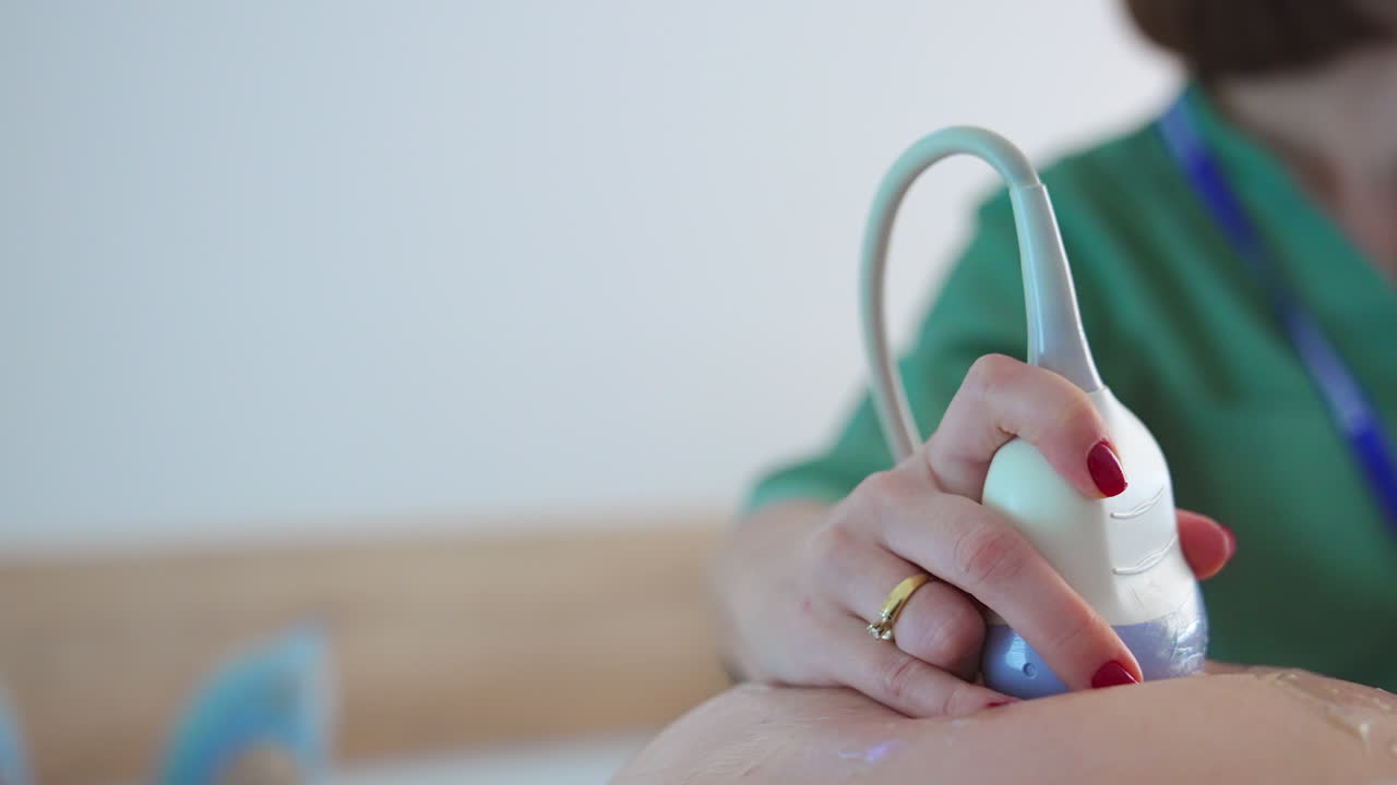 Doctor pressed ultrasound device to a pregnant belly. Close up. Future mom at obstetrician's examination.