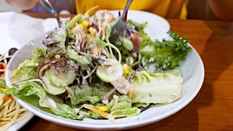 Hand-woman-Mixing-Green-Salad-In-a-glass-bowl