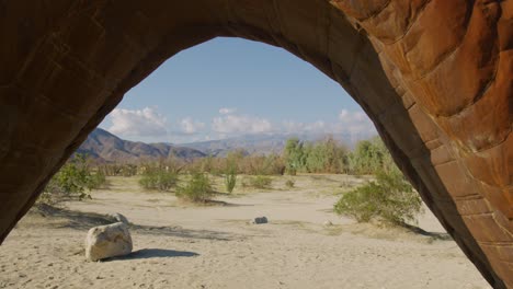 pull away shot of the desert landscape surrounded by mountains while the camera reveals the tail of a dragon statue